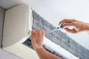 Regular AC maintenance - Close-up of a male technician's hand working on an air conditioner inside a home.